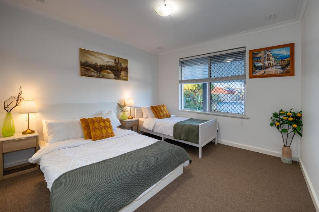 1 Schlafzimmer mit 2 Betten und einem Fenster in der Unterkunft Cozy 5 bed House Nr Airport/DFO/Casino in Perth