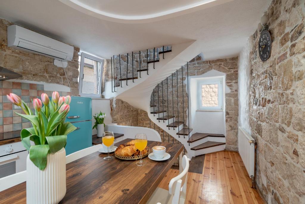 uma cozinha e sala de jantar com uma mesa e escadas em Manero em Trogir