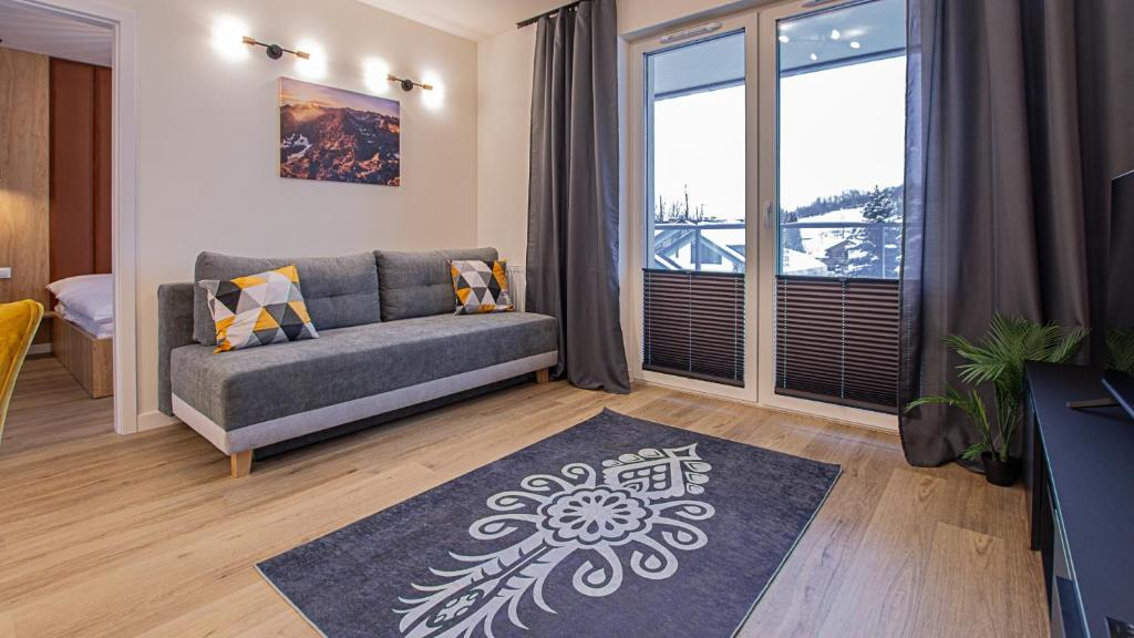 a living room with a couch and a large window at VacationClub - Apartamenty Zakopiańskie Apartament 144 in Zakopane