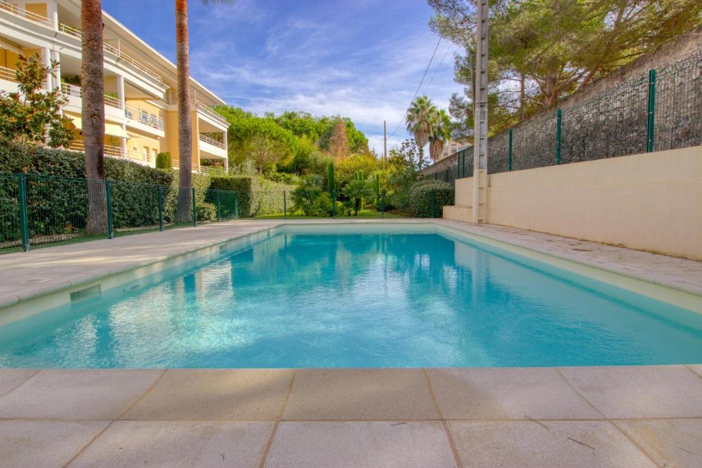 une piscine avec de l'eau bleue devant un immeuble dans l'établissement Golfe Juan - 4 People - Swimming Pool - Private Parking, à Vallauris