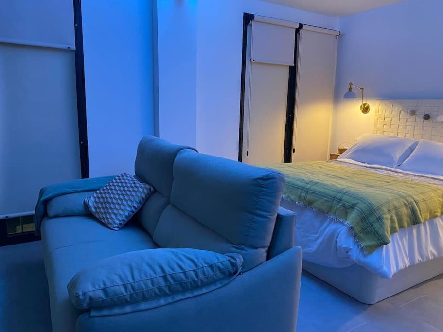 um quarto azul com um sofá e uma cama em Encantador y la mejor ubicación em Alcalá del Júcar