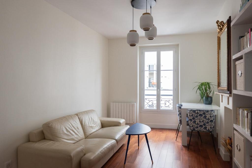 a living room with a couch and a table at Refurbished love nest on Montmartre hilltop in Paris