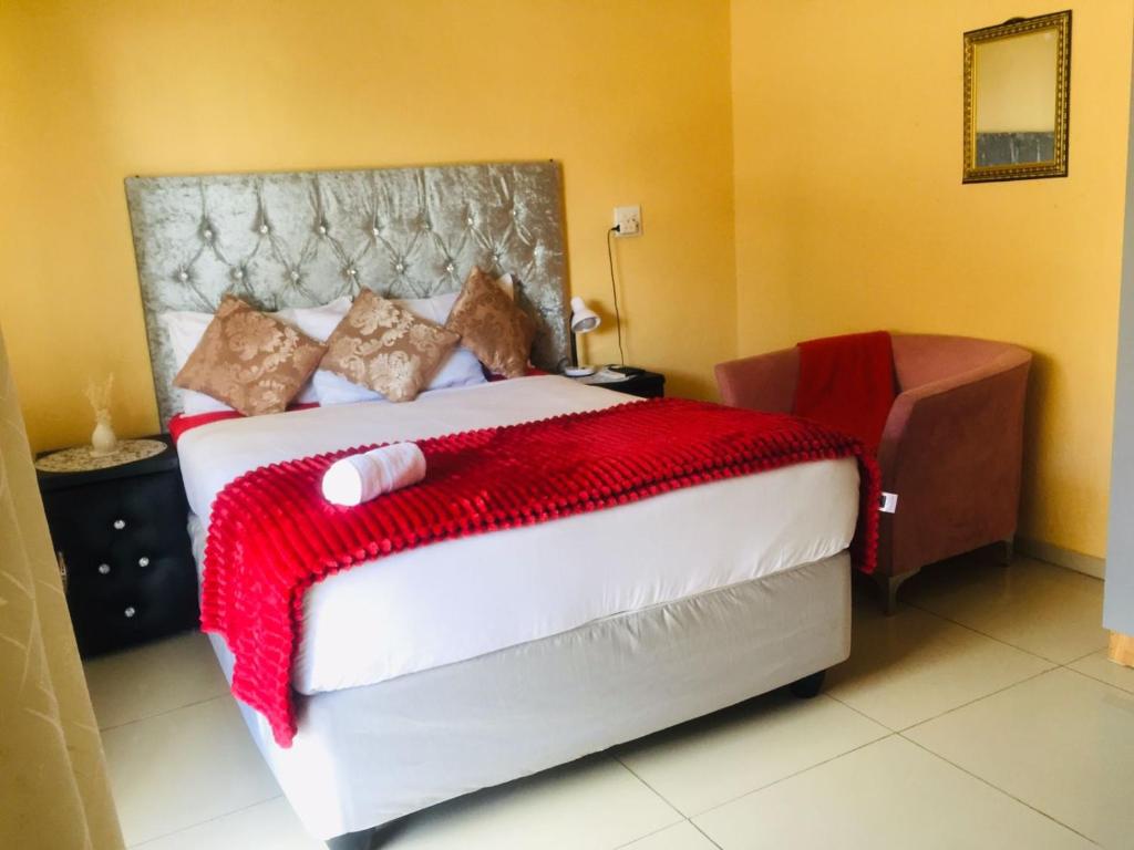 a bedroom with a large bed with a red blanket at Eliza Guest House in Empangeni