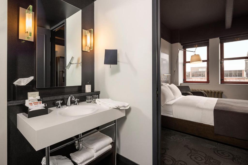 a bathroom with a sink and a bed at Hôtel Le Germain Québec in Quebec City