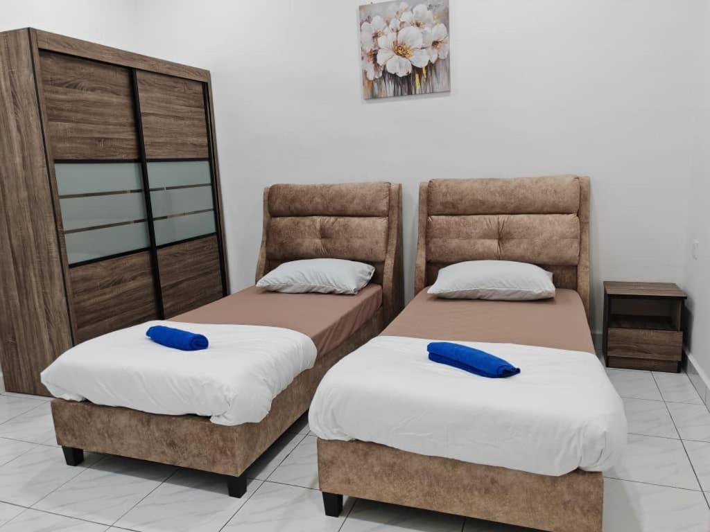twee bedden in een kamer met twee blauwe kussens bij Favourite Homestay Melaka in Melaka