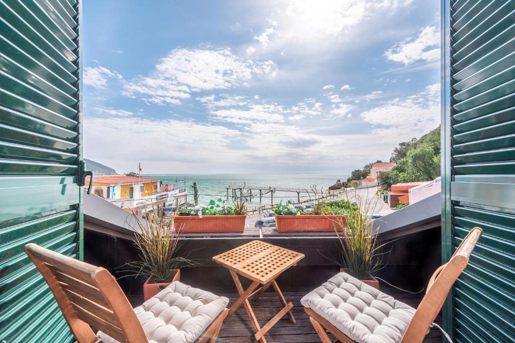 d'un balcon avec des chaises et une table offrant une vue sur l'océan. dans l'établissement Seaside Haven Beach House or Studio Retreat, à Azeitão