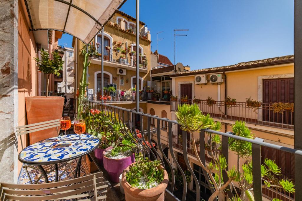 a balcony with a table and chairs and potted plants at Cascabella Taormina in Taormina