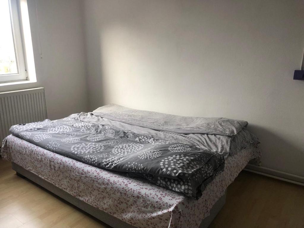 ein unmaskiertes Bett in einem Zimmer mit Fenster in der Unterkunft Camelia Apartment with a breakfast in Subotica