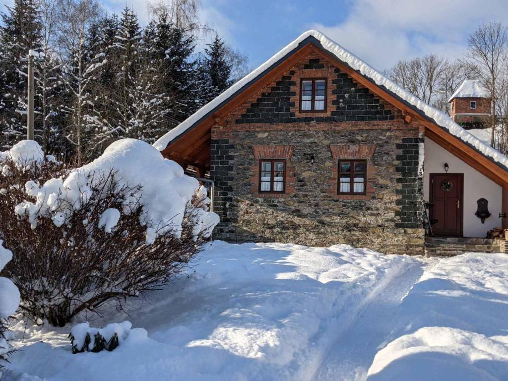 Chalupa u Anenské في Žďárský Potok: منزل حجري في الثلج المقابل