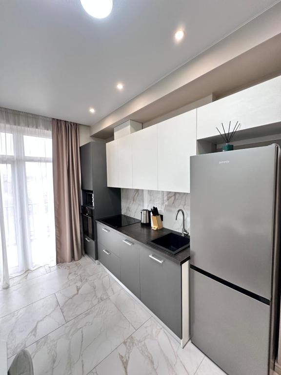 una cucina con armadietti bianchi e frigorifero di Luxury Apartments Prestige a Užhorod