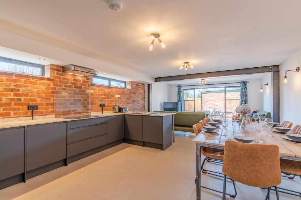 una cocina con una mesa larga y una pared de ladrillo en Norton Coach House, en Cheltenham