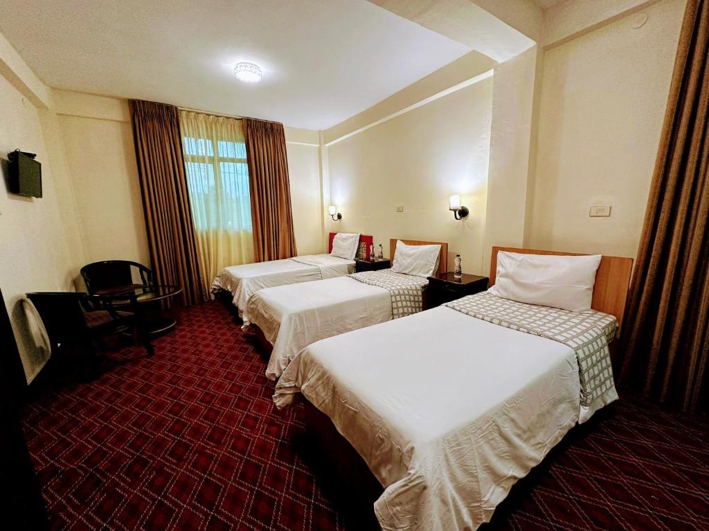 ein Hotelzimmer mit 3 Betten und einem Fenster in der Unterkunft Keba Guest House in Addis Abeba