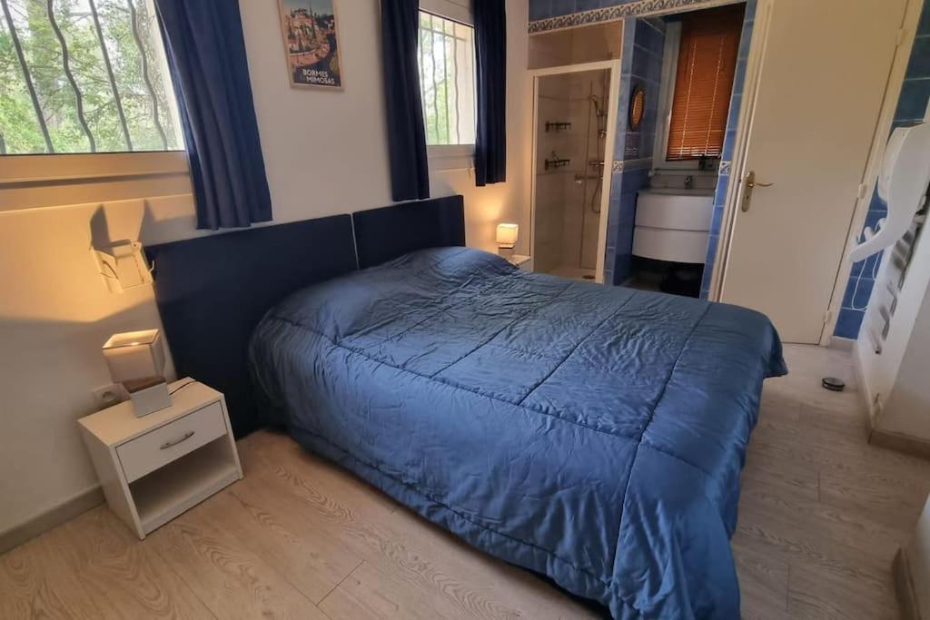 een slaapkamer met een blauw dekbed op een bed bij La porte du Soleil in Bagnols-en-Forêt
