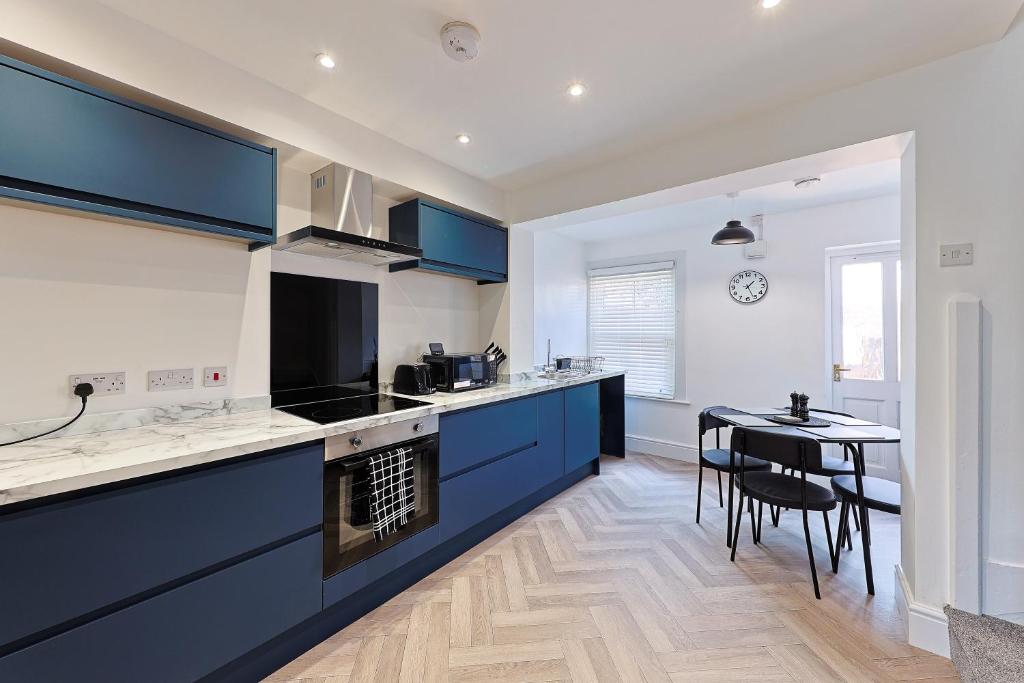 a kitchen with blue cabinets and a table in it at City Centre Riverside Retreat in Kent