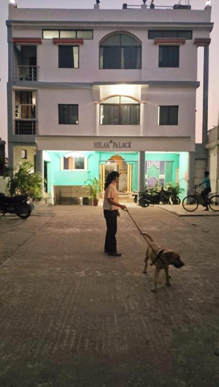 a person with a dog on a leash in front of a building at Milan Palace Deoghar in Deoghar