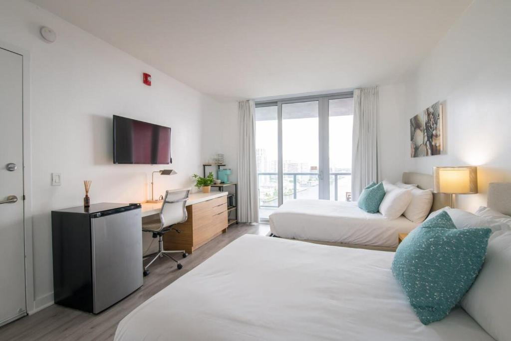 1 dormitorio con 2 camas y escritorio con ordenador en Spectacular View wBalcony Pool, en Hallandale Beach