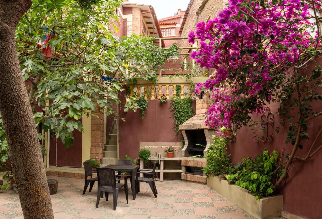 un patio con mesa, sillas y flores púrpuras en Casa Martinez en Sucre