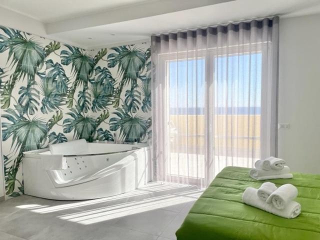 BLU MARINE في كاتانزارو: غرفة نوم مع حوض استحمام وسرير أخضر مع مناشف