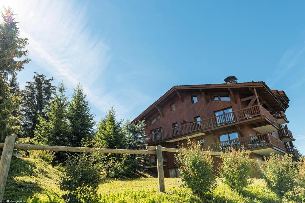 a building on a hill with a wooden fence at Résidence Pierre &amp; Vacances Premium Les Alpages de Chantel in Arc 1800