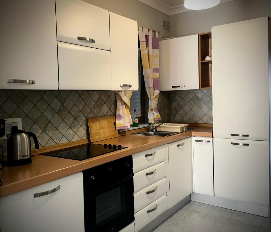 a kitchen with white cabinets and a stove top oven at City Center Apartments in Mellieħa