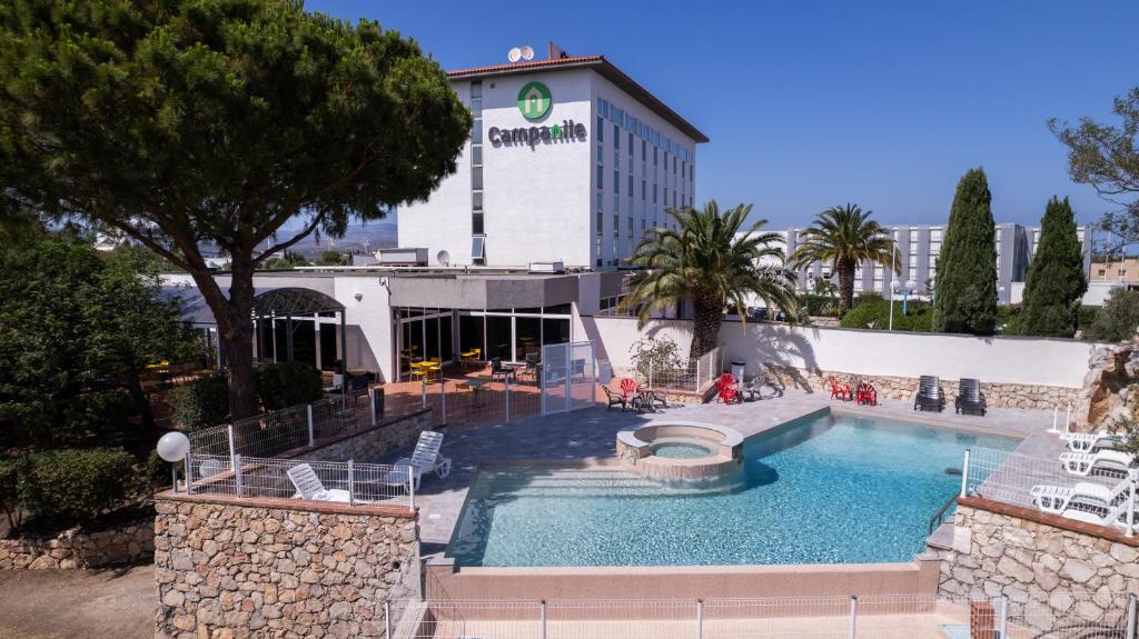 um hotel com piscina em frente a um edifício em Campanile Perpignan Aéroport em Rivesaltes