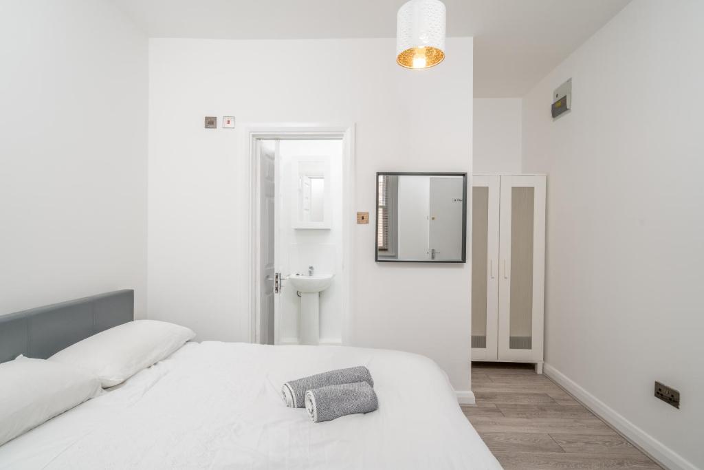 a white bedroom with a bed and a mirror at Cozy Studio Flat- Dalston Central in London