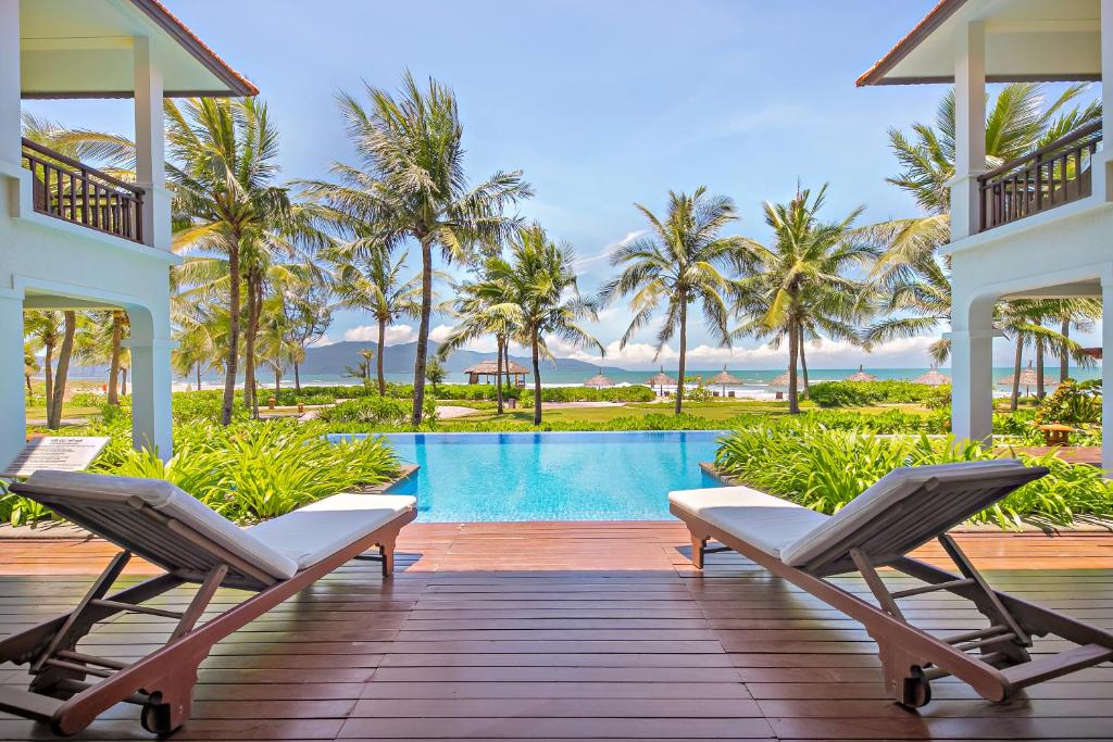a resort deck with chairs and a swimming pool at Abogo Champa Villa Beach Da Nang in Da Nang