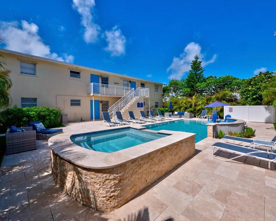 a swimming pool with chairs and a building at 2BR Near The Beach !Walk 2 Everything! in West Palm Beach