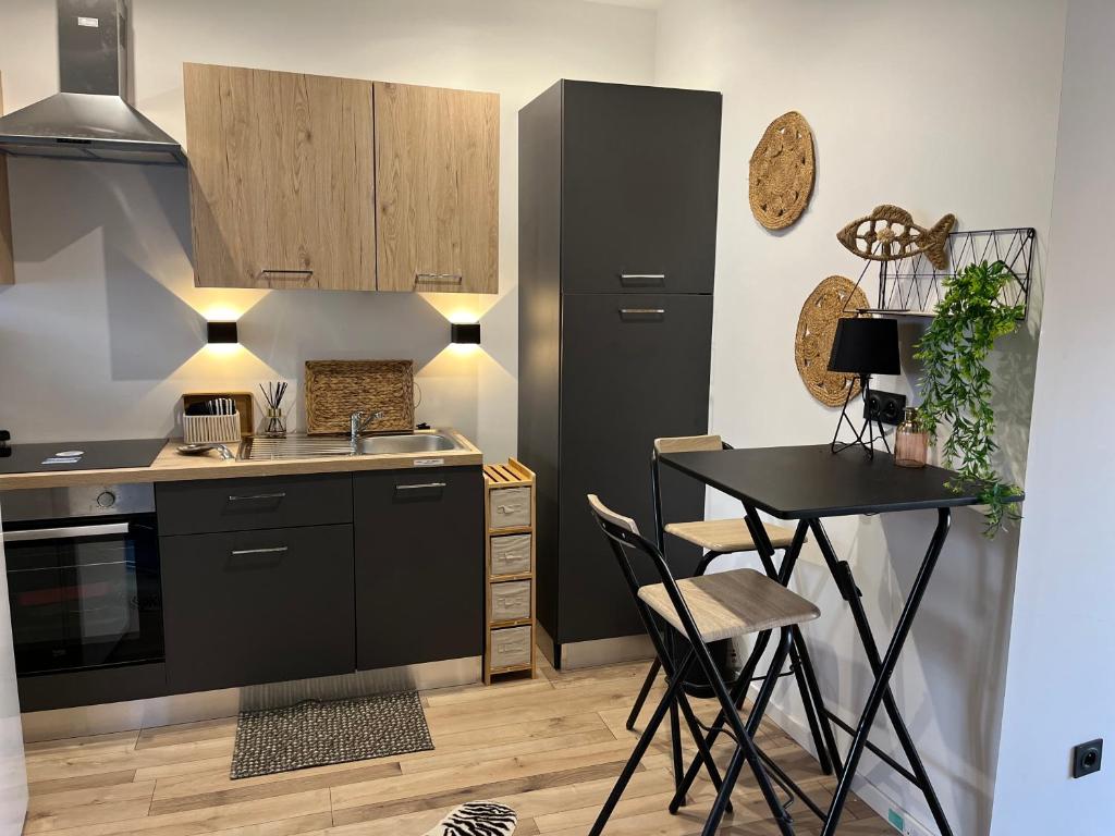a kitchen with a table and a black refrigerator at studio Lauralex in Montardon