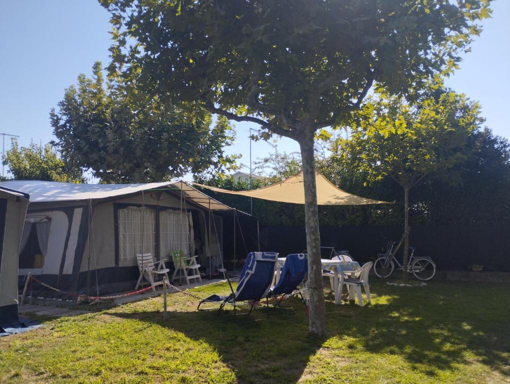 uma tenda com cadeiras, uma mesa e uma árvore em Camping Mayer em Cavallino-Treporti