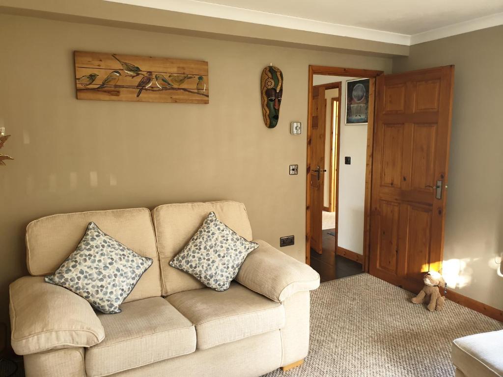 a living room with a couch with two pillows on it at Cosy Pembrokeshire Home in Pembrokeshire