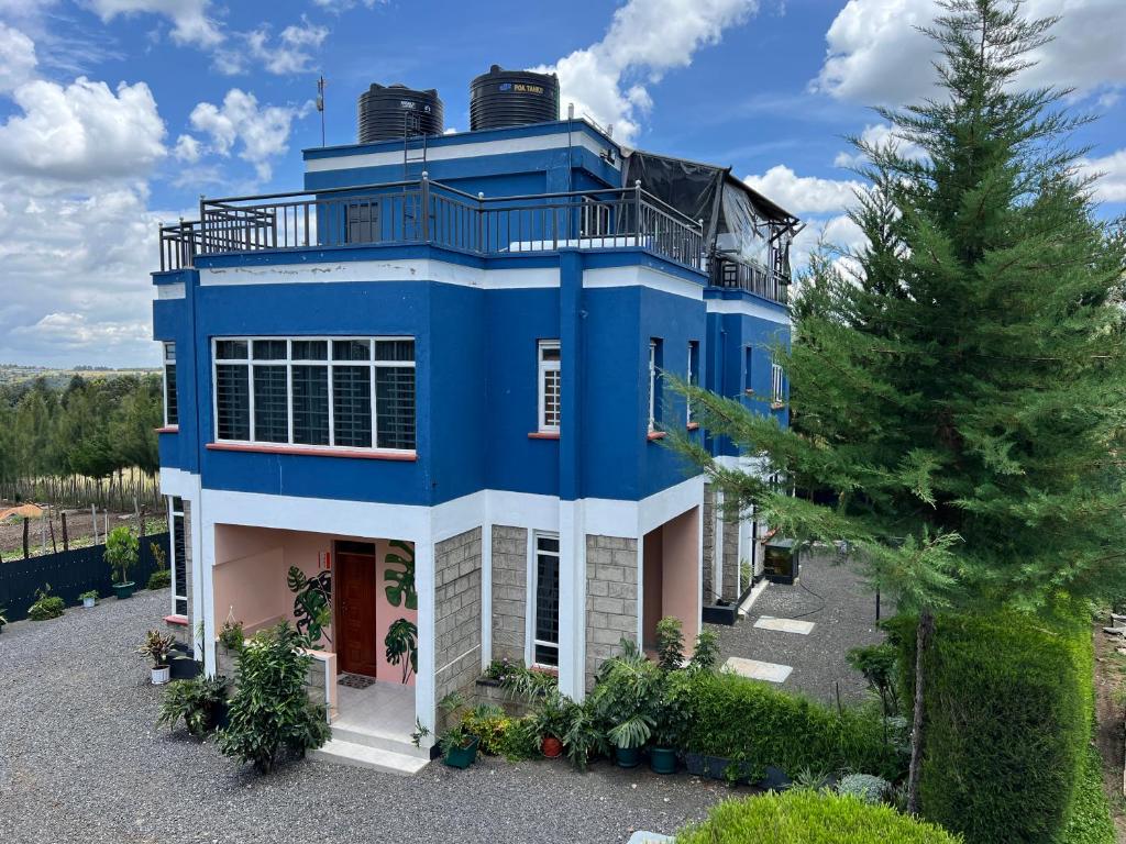 una casa azul con un árbol delante en The Fairway Residence, en Nyeri