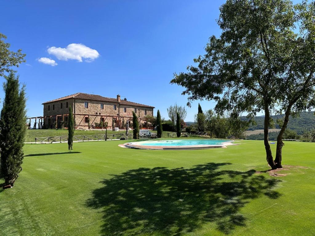 a large green yard with a building and a swimming pool at Tenuta Cantona in Casole dʼElsa