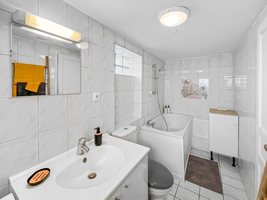 een witte badkamer met een wastafel en een toilet bij L'Écrin de Noiseau in Noiseau