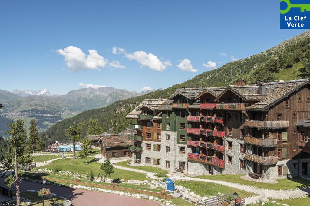 un grand bâtiment au bord d'une rivière dans l'établissement Résidence Pierre & Vacances Premium Arc 1950 Le Village, à Arc 1950