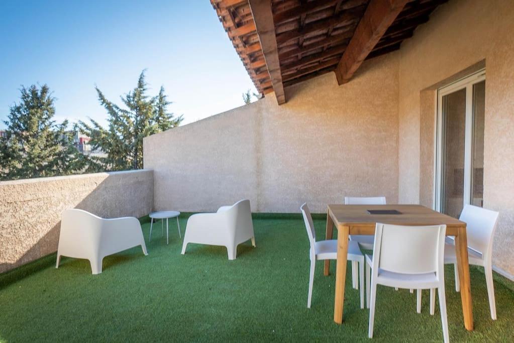 een patio met een tafel en stoelen op het gras bij La Terraza, T2 avec Clim, Parking, Port Marianne in Montpellier