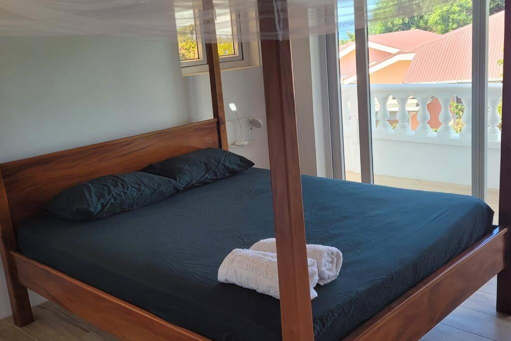 a bed with a wooden frame with a towel on it at 3 master bedrooms All-in-one in Roseau