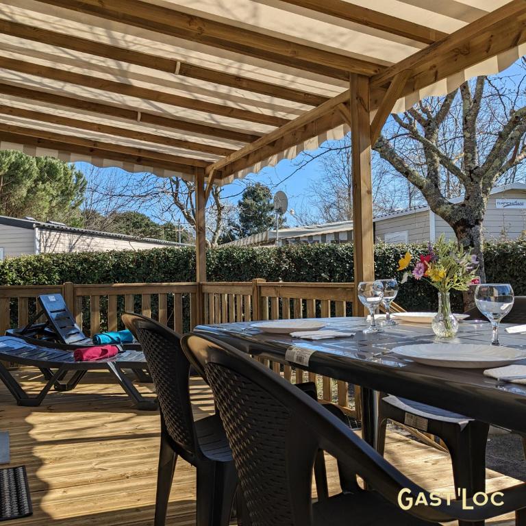 un patio avec une table et des chaises sous une pergola en bois dans l'établissement Le Rêve bleu MOBIL HOME 49 3 CHAMBRES, à Gastes