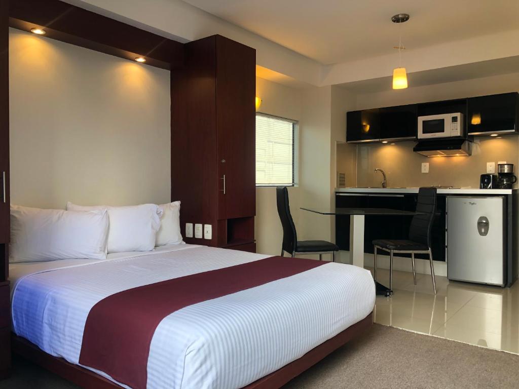 A studio-style suite combines a double bed with a compact kitchen and small dining-work area.
