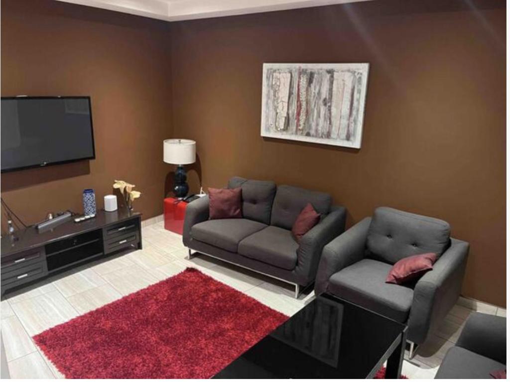 sala de estar con 2 sofás y TV de pantalla plana en Wynn Apt - Luxe / Uninterrupted Power / Near Mall / Sleeps 3, en Kumasi