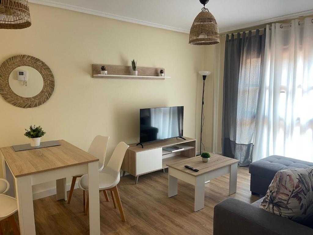een woonkamer met een televisie en een tafel bij Apartamento Cueto II in Soto del Barco