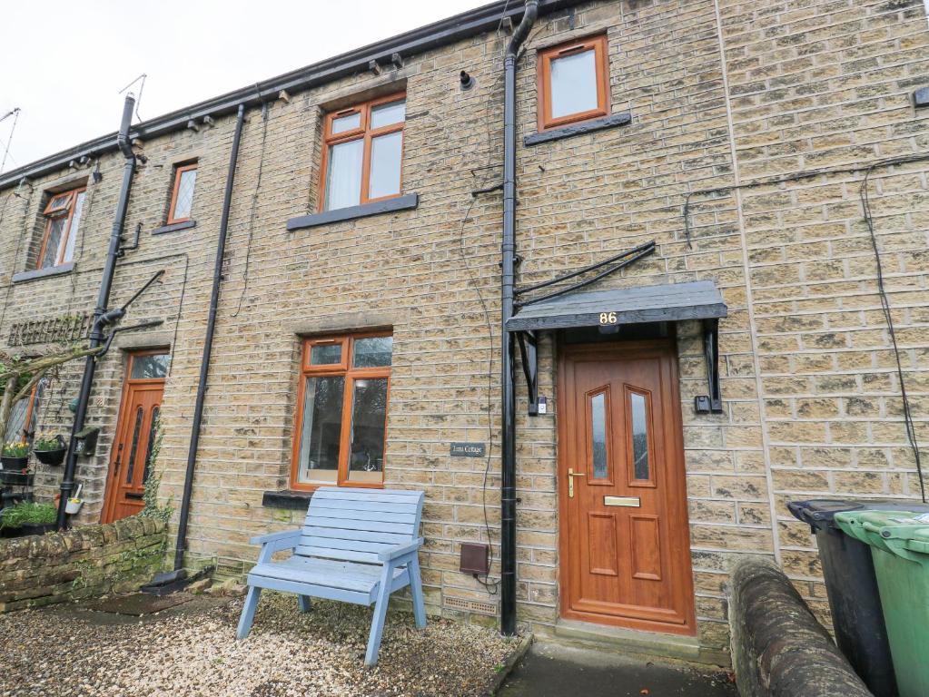 a blue chair sitting outside of a brick building at Luna Cottage in Holmfirth