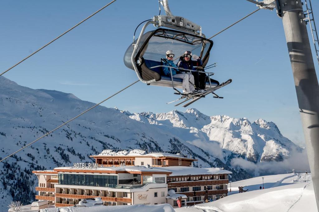 twee personen op een skilift in de bergen bij SKI - GOLF - WELLNESS Hotel Riml in Hochgurgl