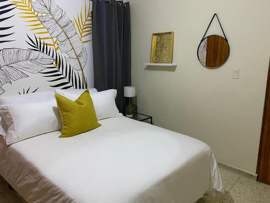 a bedroom with a white bed with yellow pillows at Gloria’s Cozy Apartment in La Romana
