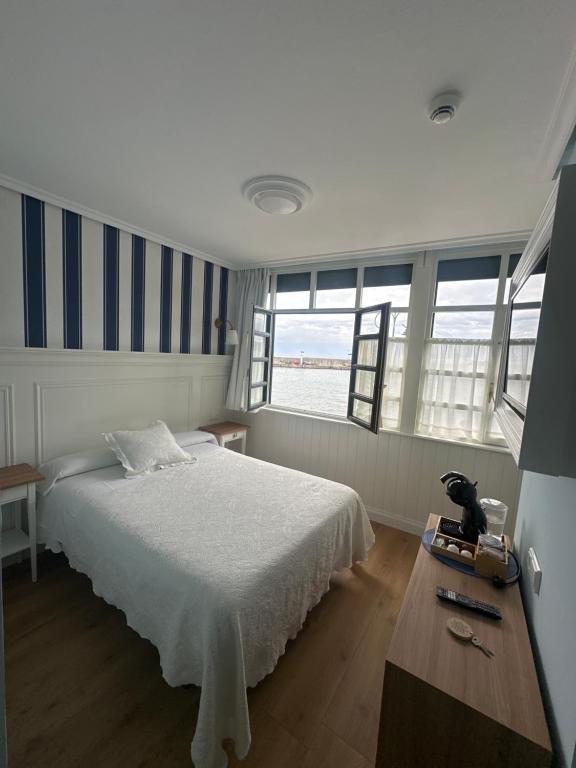 a bedroom with a bed and a table and windows at Hotel El Pescador in Tazones