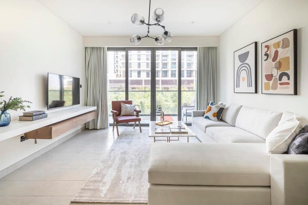 uma sala de estar com um sofá branco e uma grande janela em Frank Porter - Sobha Hartland Greens em Dubai