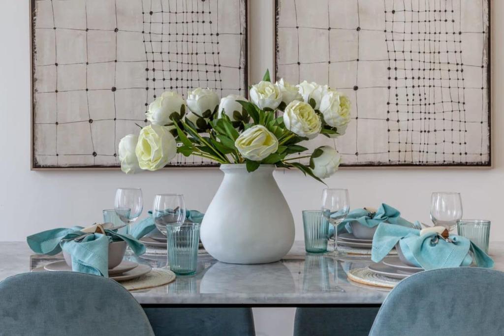 a white vase with white flowers on a table at Frank Porter - BLVD Heights T1 in Dubai