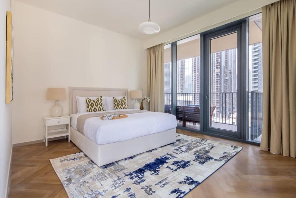 a white bedroom with a bed and a large window at Frank Porter - BLVD Heights T1 in Dubai