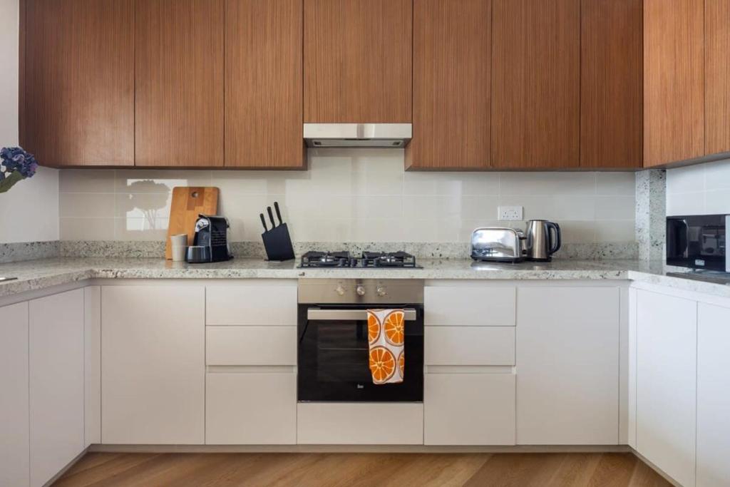 a kitchen with white cabinets and a stove top oven at Frank Porter - BLVD Heights T1 in Dubai