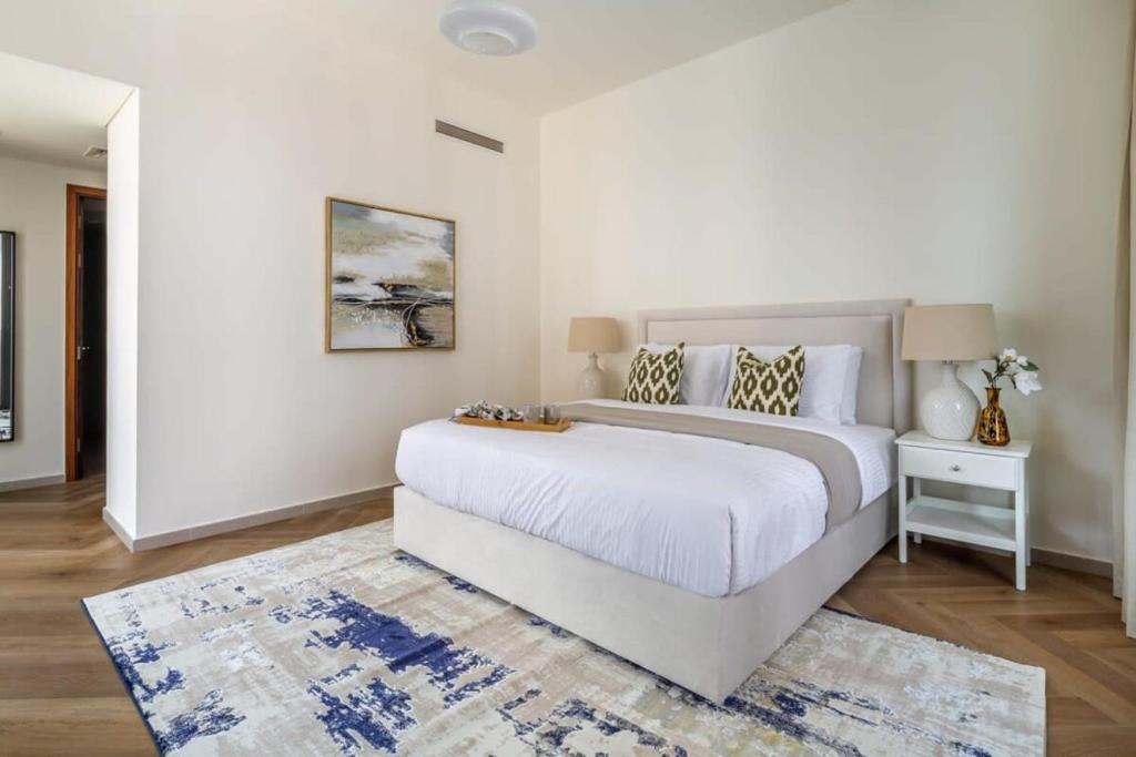 a white bedroom with a large bed and a rug at Frank Porter - BLVD Heights T1 in Dubai